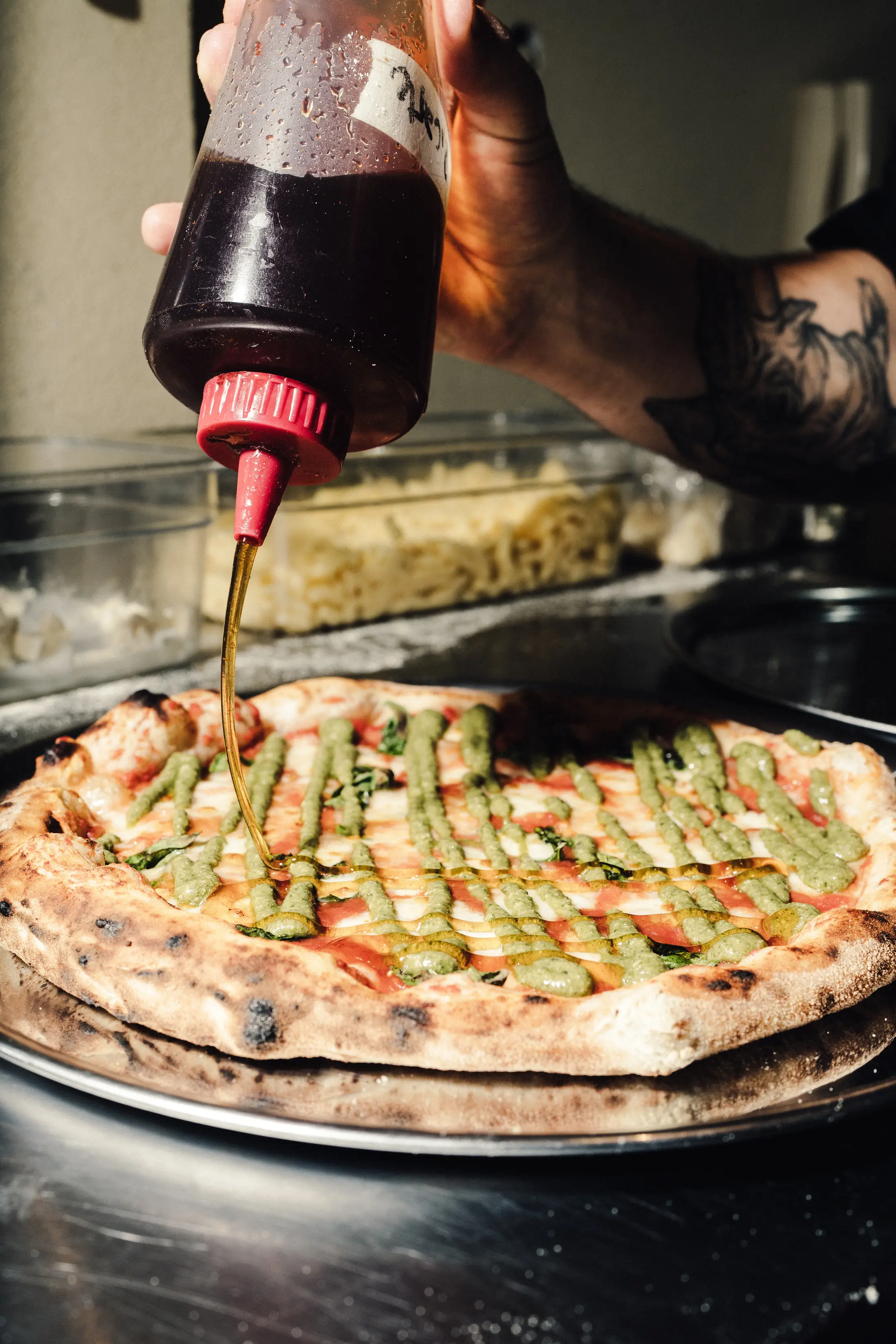 Miel picante cayendo sobre una pizza de pesto recién horneada