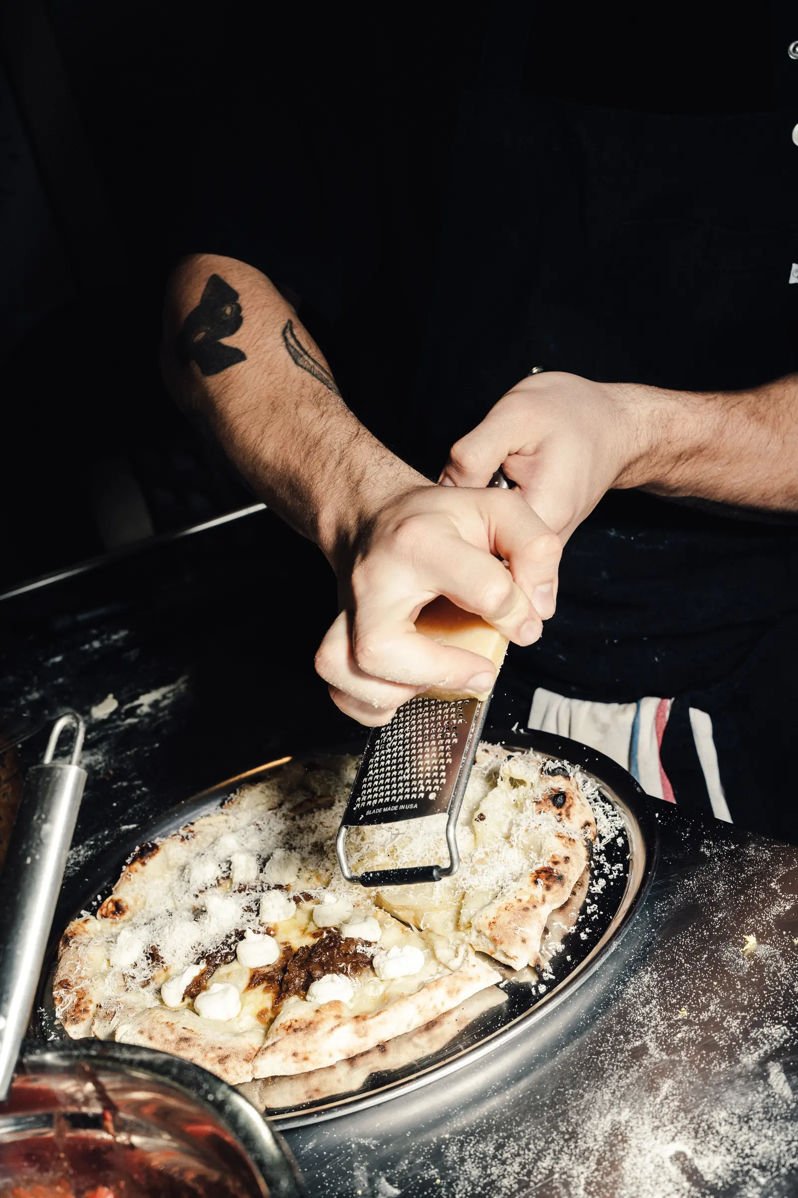 Queso rallado a mano sobre una pizza recién salida del horno